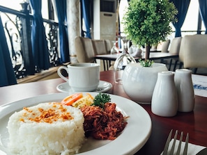 A table with a plate of food, a cup, a teapot, and salt and pepper shakers. - Fernandina 88 Suites Hotel (QUEZON CITY)