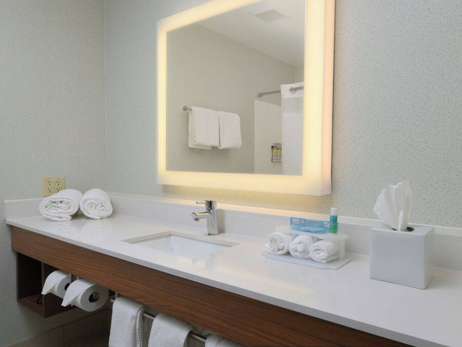 Une salle de bain avec un lavabo blanc, un miroir et un porte-serviettes.