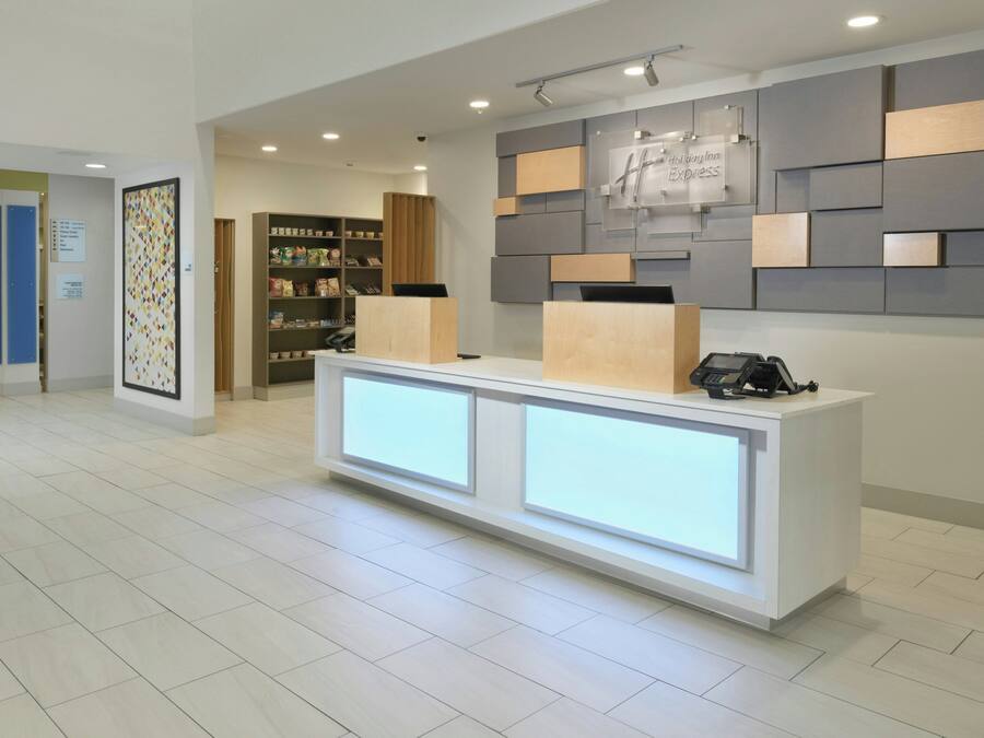 A hotel reception area with a modern design, including a reception desk with a built-in phone and a digital display.