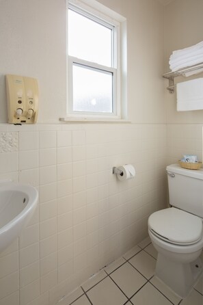 A small, clean bathroom with a toilet, sink, and hand dryer.