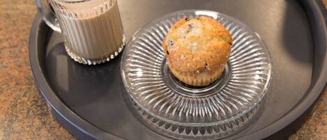 A clear glass mug with a handle and a muffin on a plate with a decorative rim.