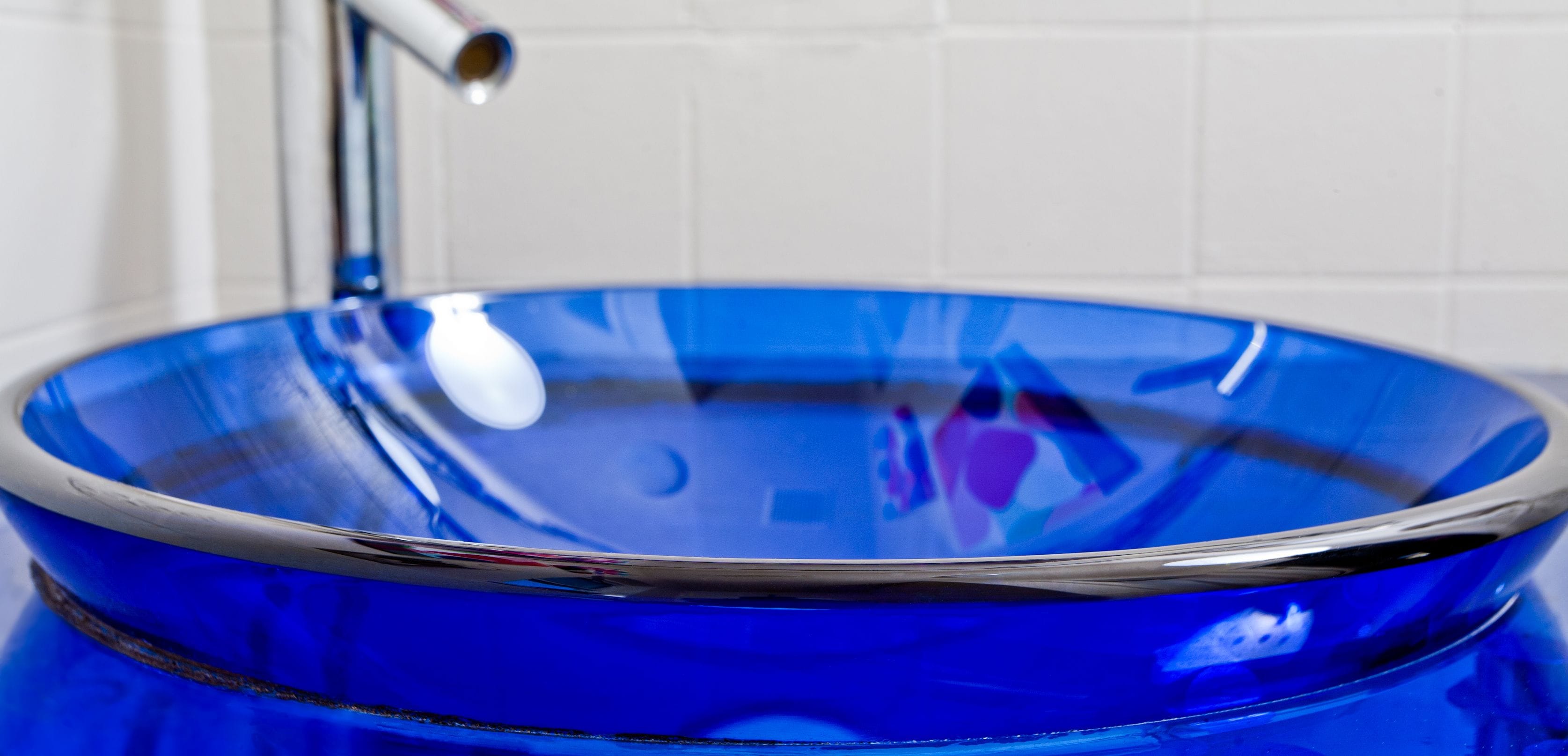 Ein blaues Waschbecken aus Glas mit einem Chromarmaturen.