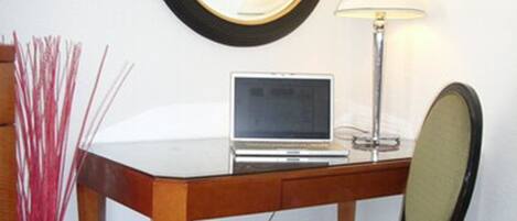 Un petit bureau comprenant un bureau, une chaise, une lampe et une horloge fixée au mur.