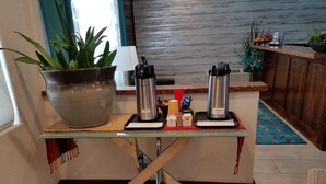A coffee station with two coffee makers, a large pot, and a tray with coffee cups and sugar packets.