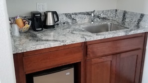 A kitchen with a built-in microwave, a coffee maker, a sink, and a dishwasher.