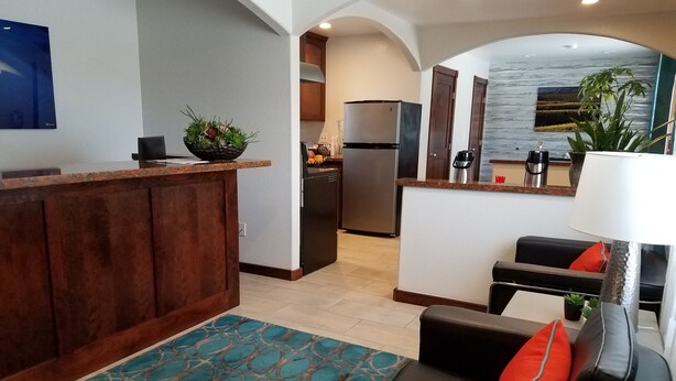A modern kitchen with a central island, a dining area with a sofa, and a living room with a lamp.