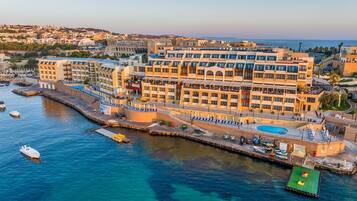 Un hotel frente al mar con un puerto deportivo, varios balcones y una piscina.