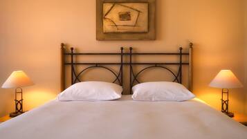 A bed with a metal headboard, two bedside lamps, and a framed artwork above the bed.