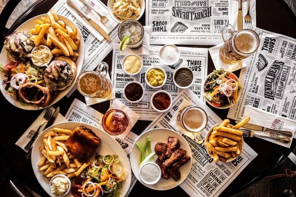 Una mesa con diversos alimentos, bebidas y periódicos.