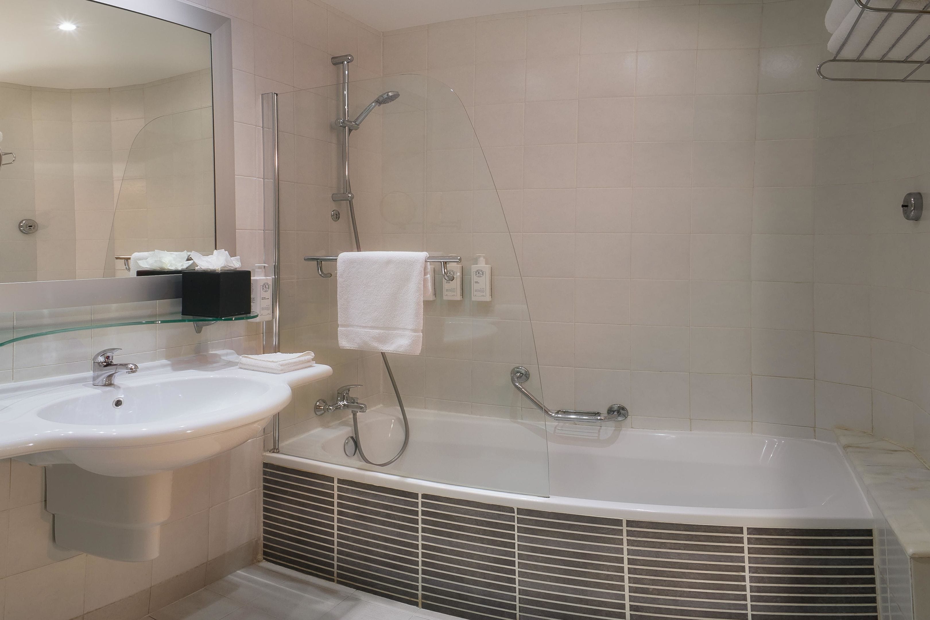 Ein modernes Badezimmer mit Waschbecken, Spiegel, Dusche und Badewanne.