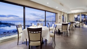 A restaurant with tables set for dining, large windows offering a view of the sea, and a modern interior design. - Verdi St Georges Bay Marina (St. Julian's)