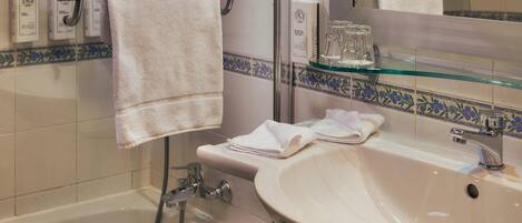 A bathroom with a bathtub, a sink, a glass shower enclosure, and a mirror.