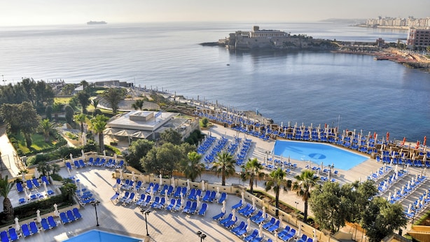 A resort with a large pool, sun loungers, and a view of the sea and a fort. - Verdi St Georges Bay Marina (St. Julian's)