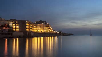 Hotel al costat del mar amb múltiples balcons i un mar tranquil.