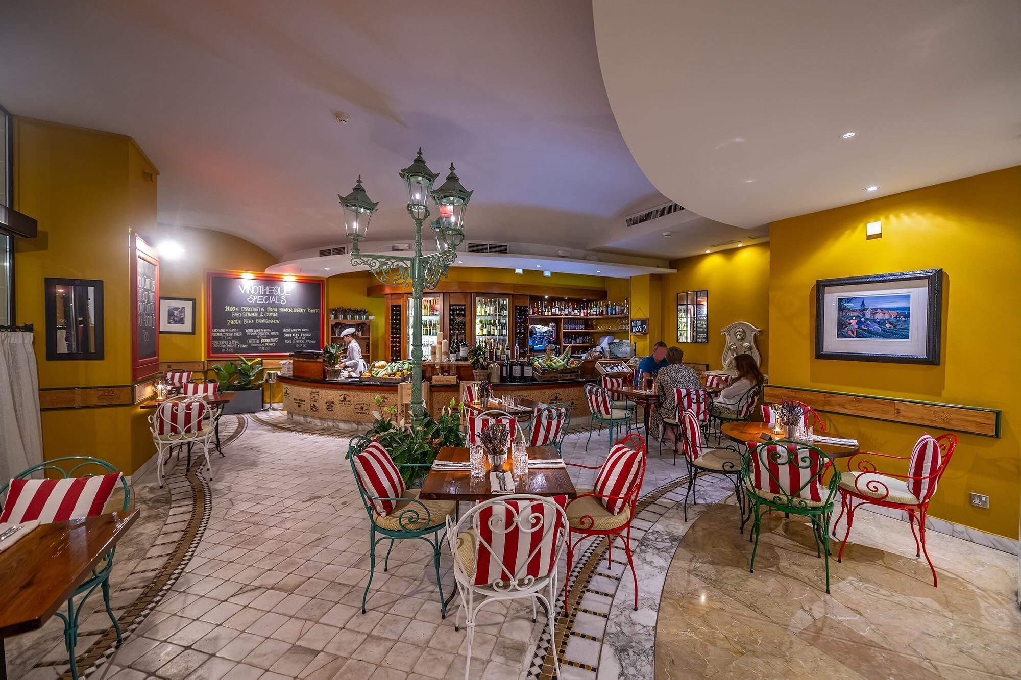 A restaurant with a bar area, multiple tables and chairs, and a menu board.