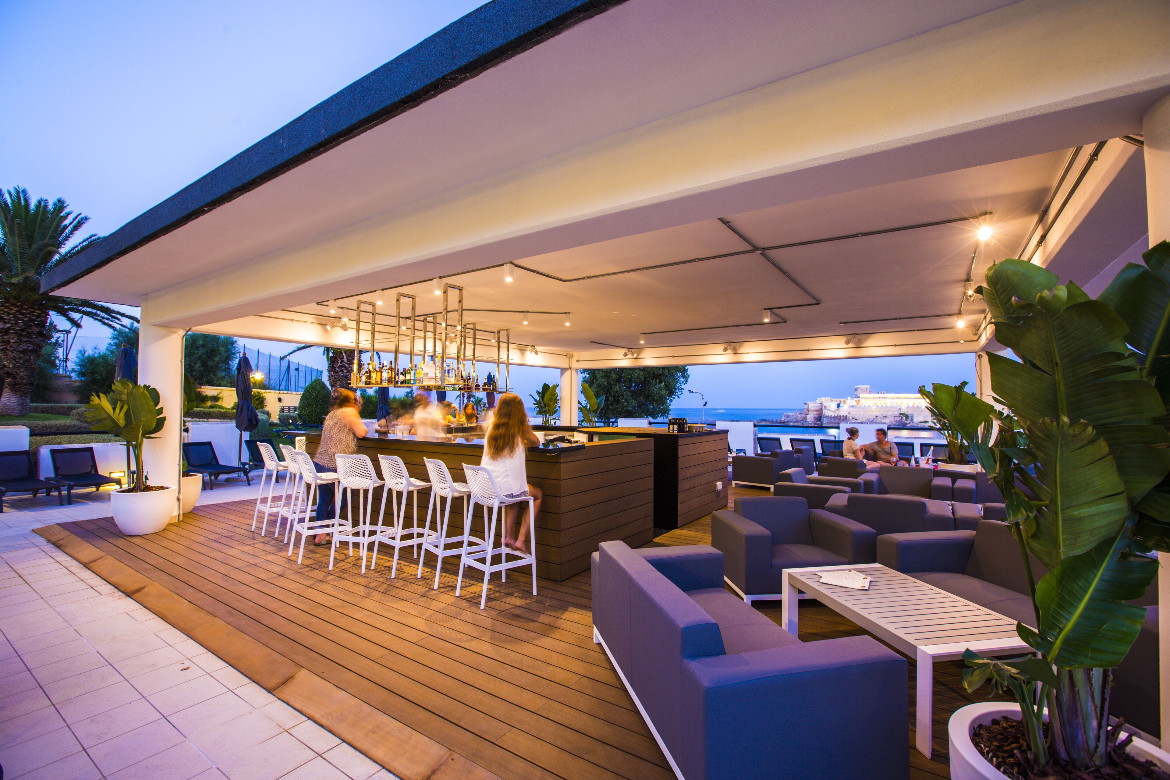 An outdoor bar area with seating and a view of the sea.