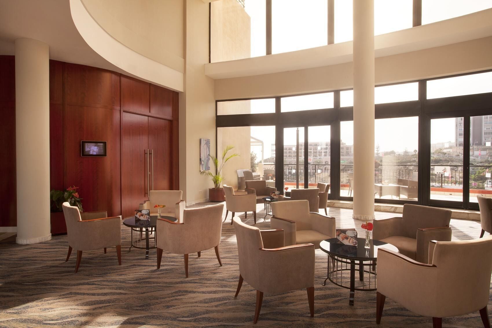 Eine geräumige Lobby mit mehreren Sitzbereichen, großen Fenstern mit Blick auf die Stadt und einem modernen Innenarchitekturstil.