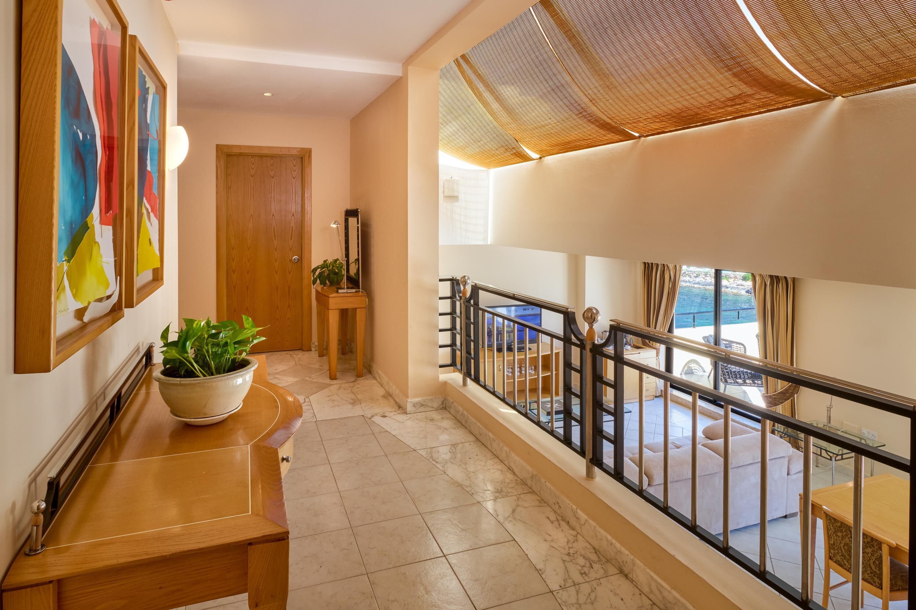 A hallway with a wooden bench, a potted plant, and a door.