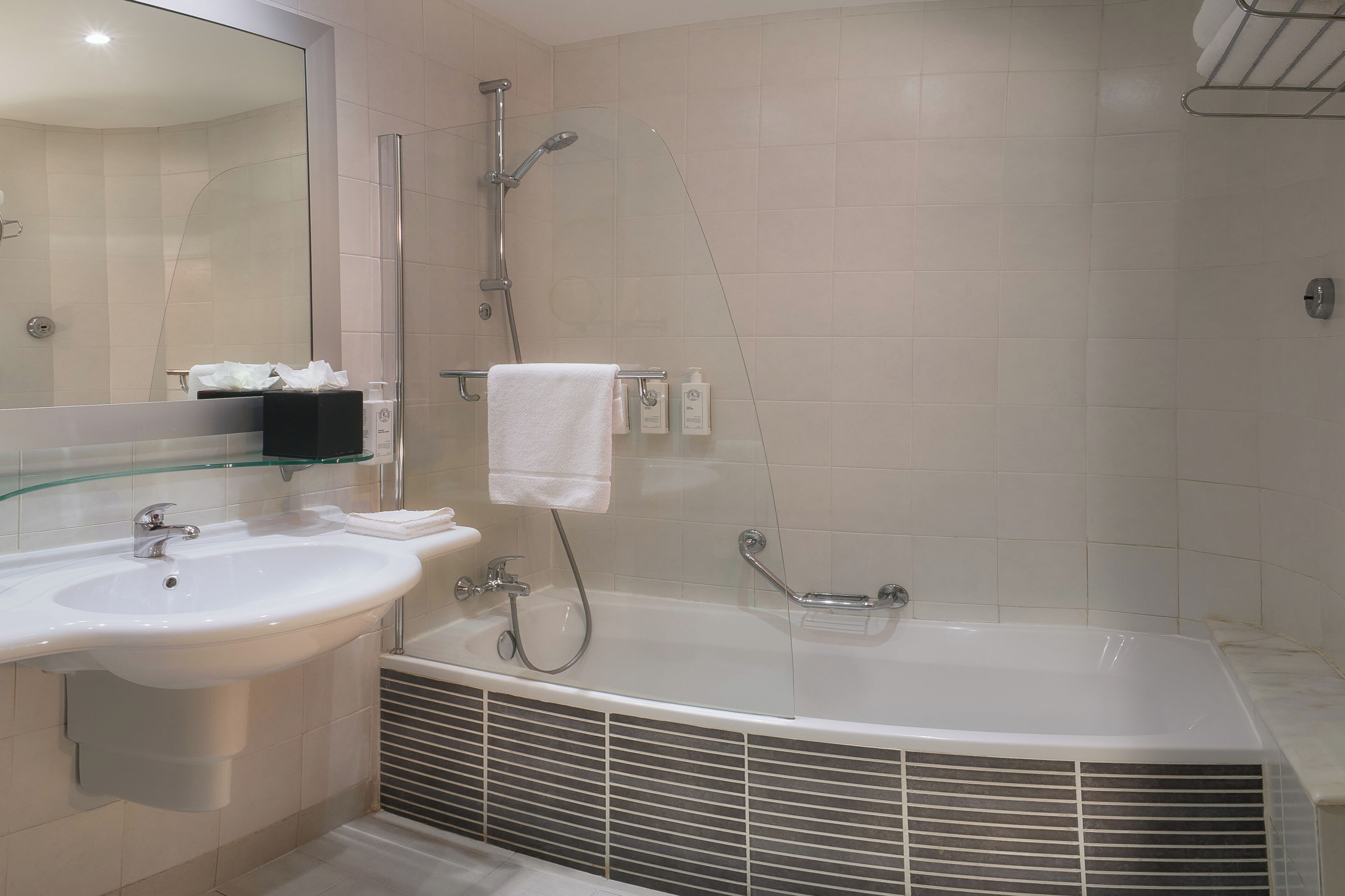 A modern bathroom with a large bathtub, a sink, and a glass shower enclosure.