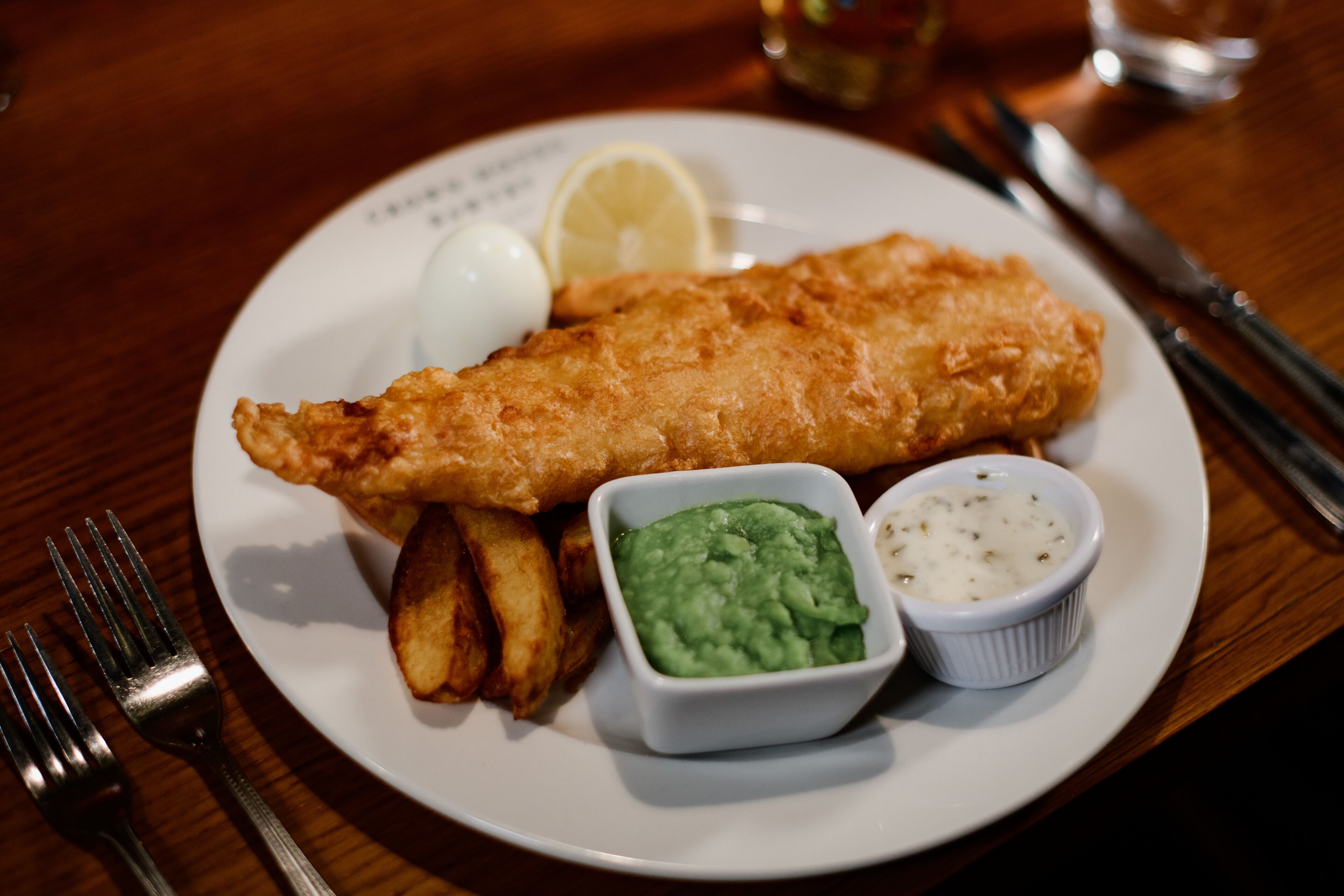Une assiette de poisson-frites, un quartier de citron et deux sauces pour tremper.