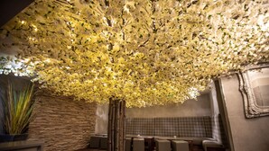 A restaurant with a stone wall, a wooden bench, and a ceiling covered in white flowers. - The Crown Hotel Bawtry, Doncaster (Doncaster)