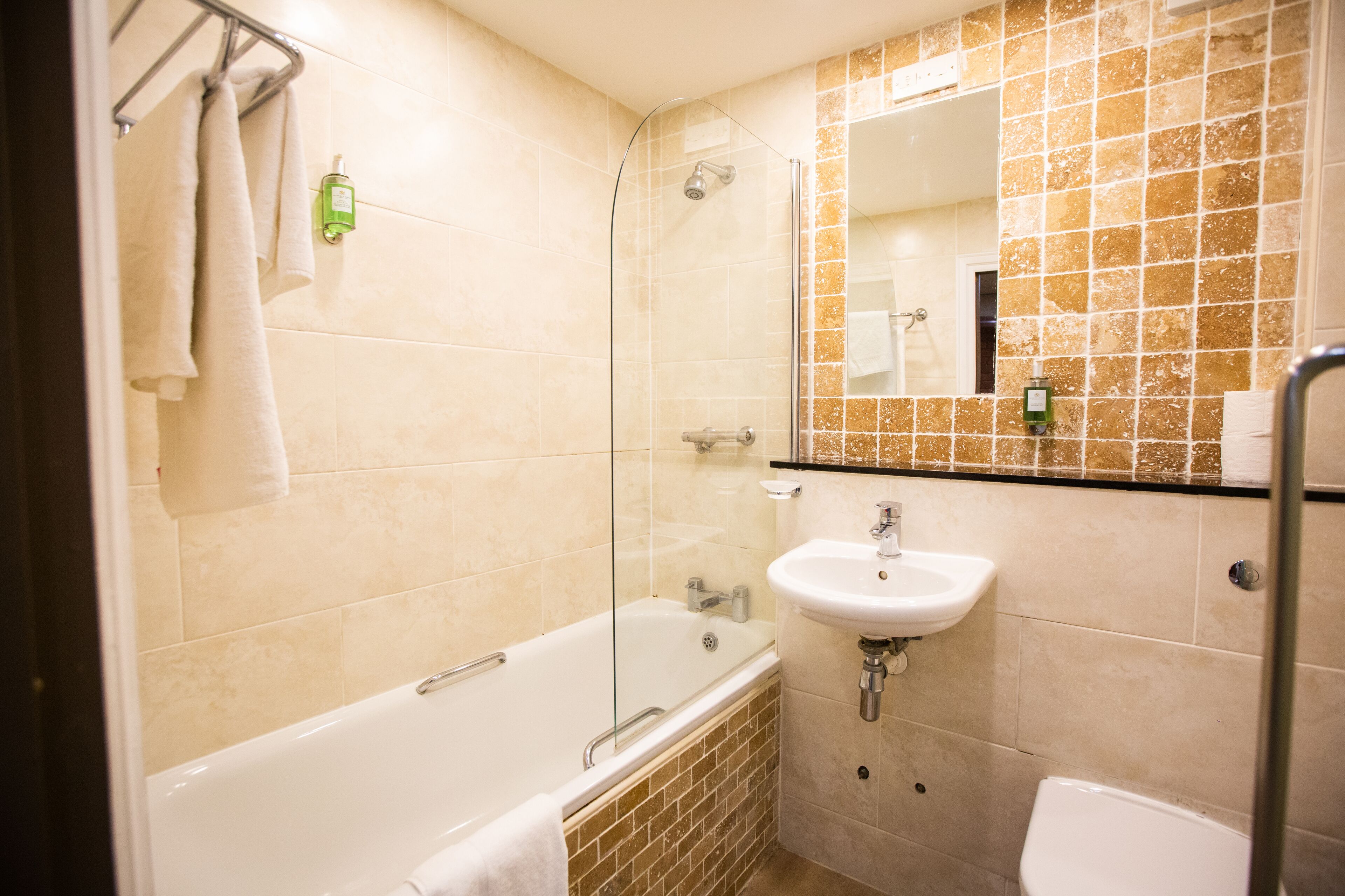 A bathroom with a glass-enclosed shower, a white sink, and a toilet.
