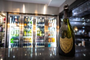 Una botella de champán Dom Perignon Vintage 2008 sobre la barra de un bar, con un fondo desenfocado.