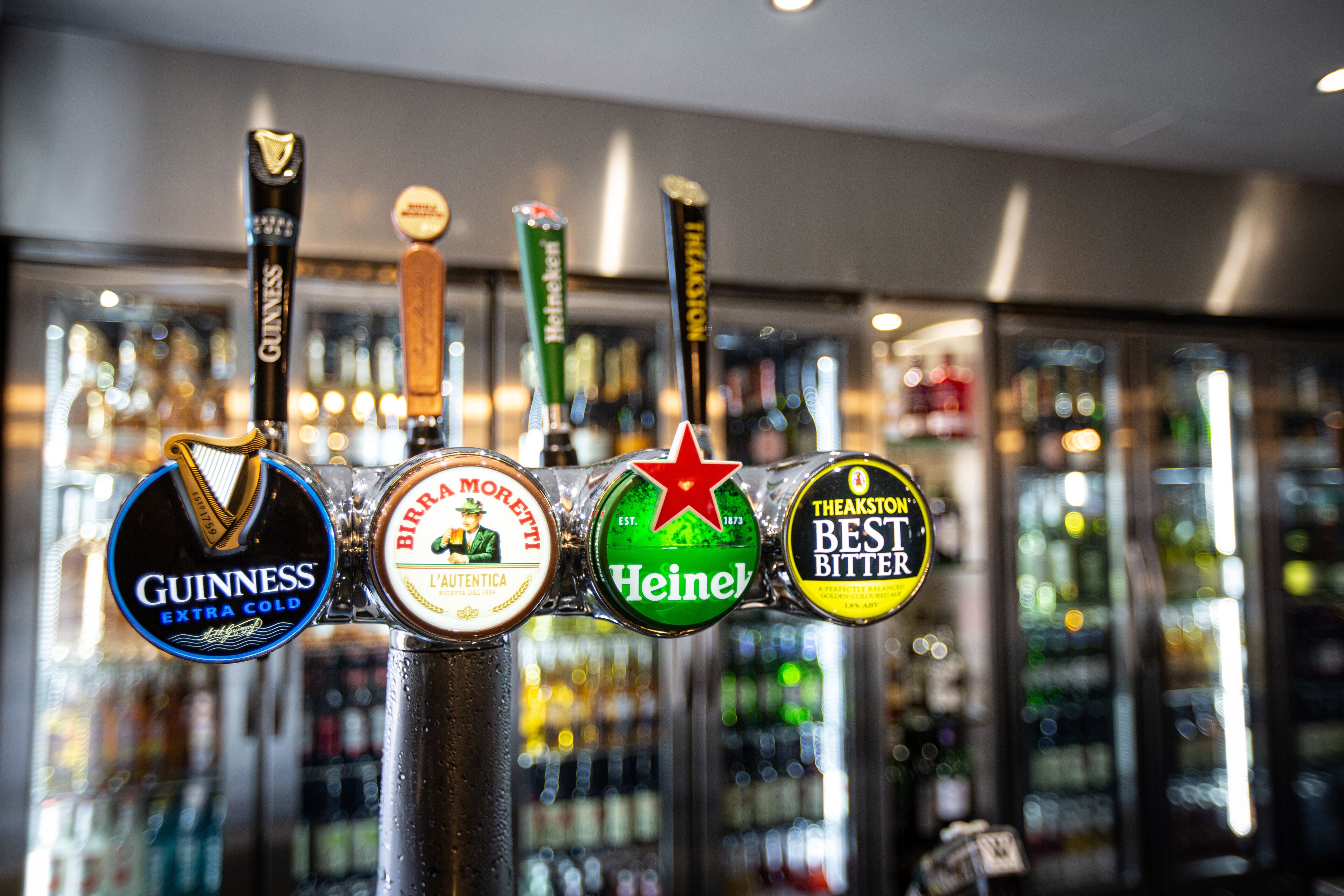 Un bar con rubinetti per birra che includono marche come Guinness, Heineken e Theakston Best Bitter.