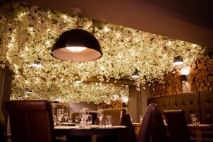 Un interior de restaurante con techo floral, pared de troncos de madera y asientos de cuero.