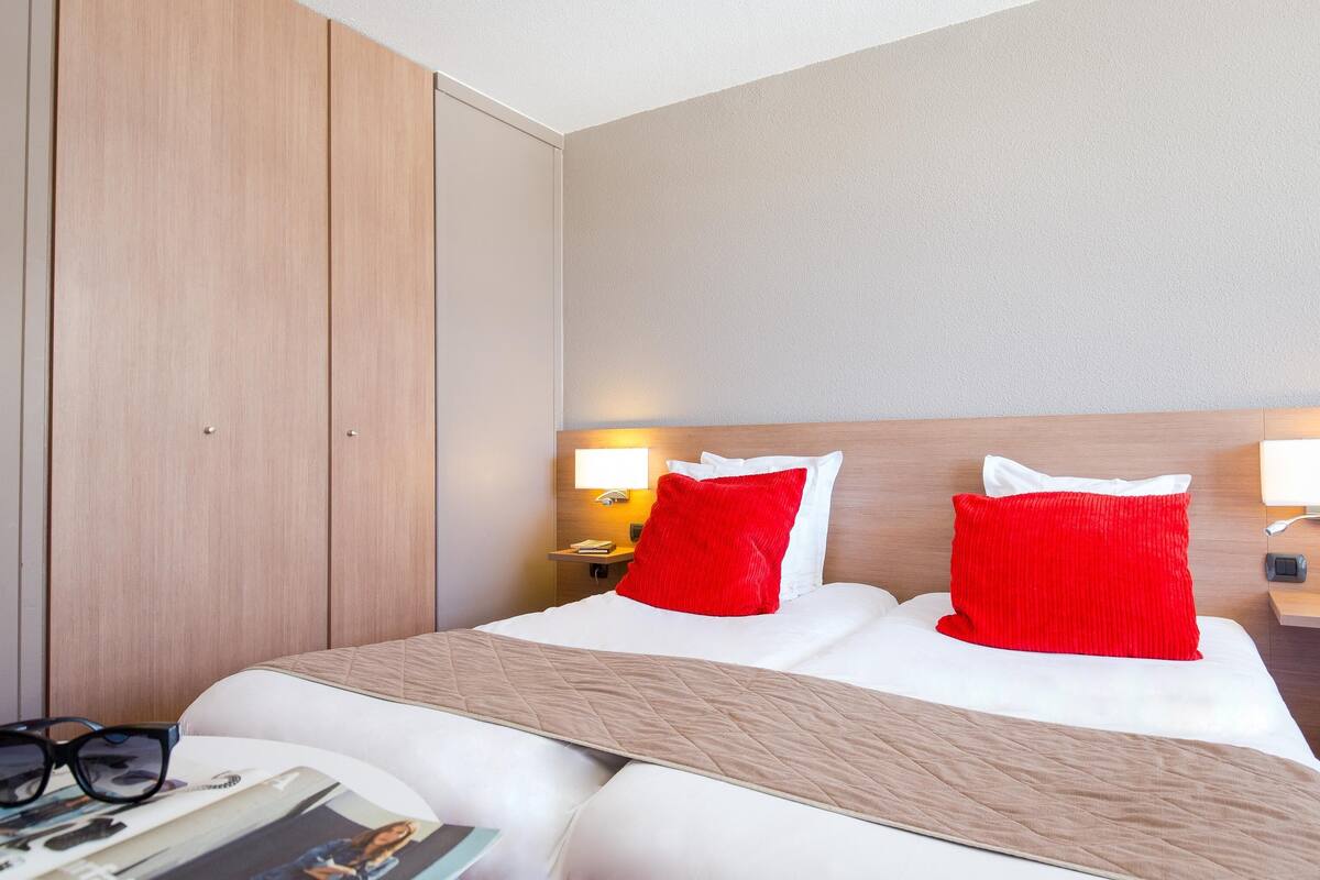 A hotel room with a bed, a nightstand, a lamp, and a wardrobe.
