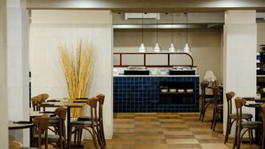 A restaurant with a checkered floor, wooden chairs, and a blue tiled counter. - c-hotels Club House Roma (Rome)