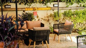 Wicker chairs with cushions, a small table, and a wall with a yellow pipe and a red sign. - c-hotels Club House Roma (Rome)
