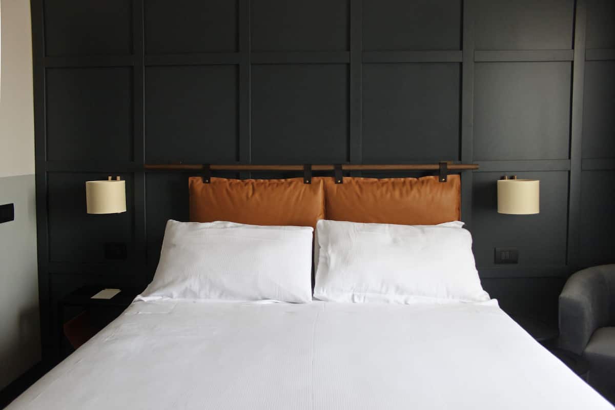 A hotel room with a large bed, dark wall paneling, and two bedside lamps.