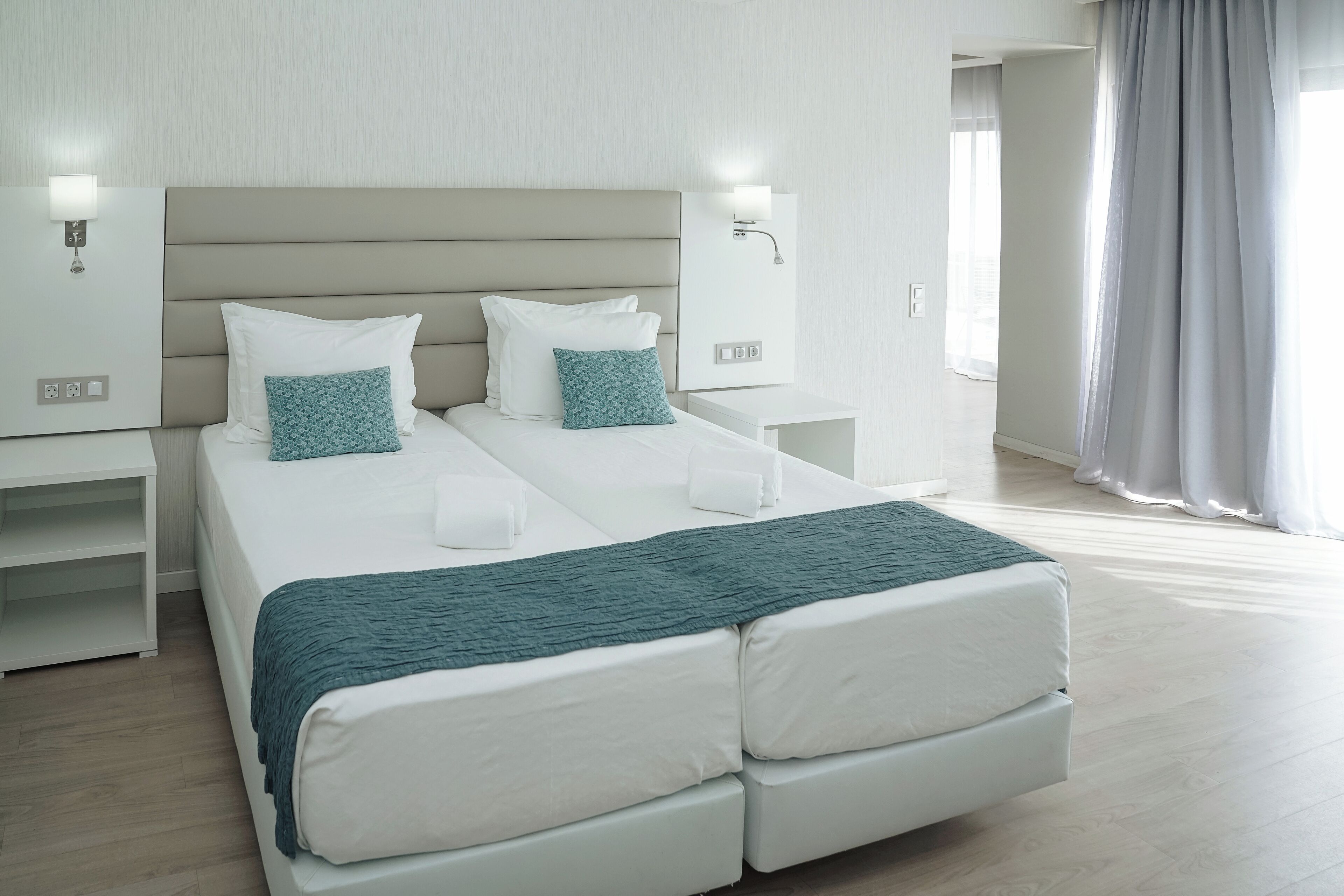 Habitación de hotel moderna con una cama grande, mesitas de noche y vistas al exterior.
