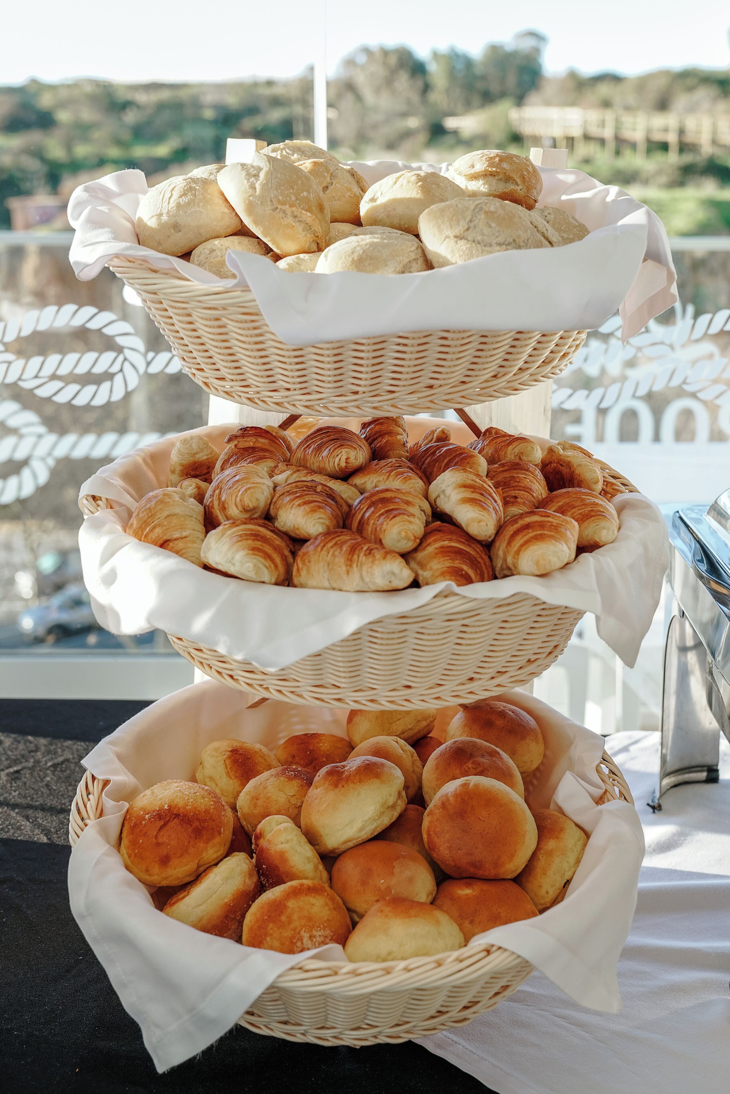 Una exhibición escalonada de pan y pasteles en cestas de mimbre sobre una mesa.