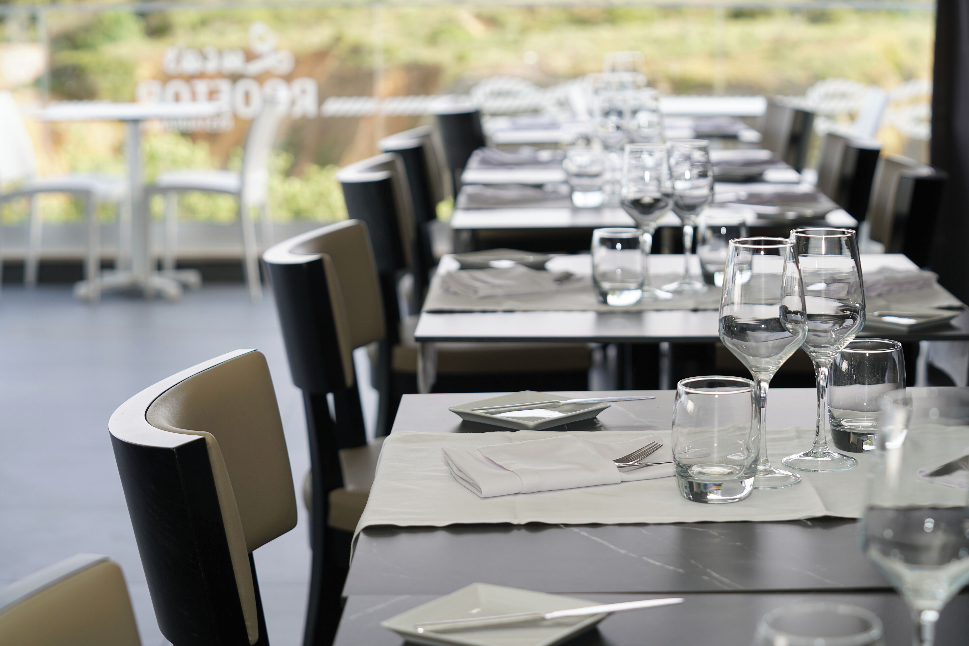 Ein Restaurant mit gedeckten Tischen, mit klarem Glas und ordentlich gefalteten Servietten.