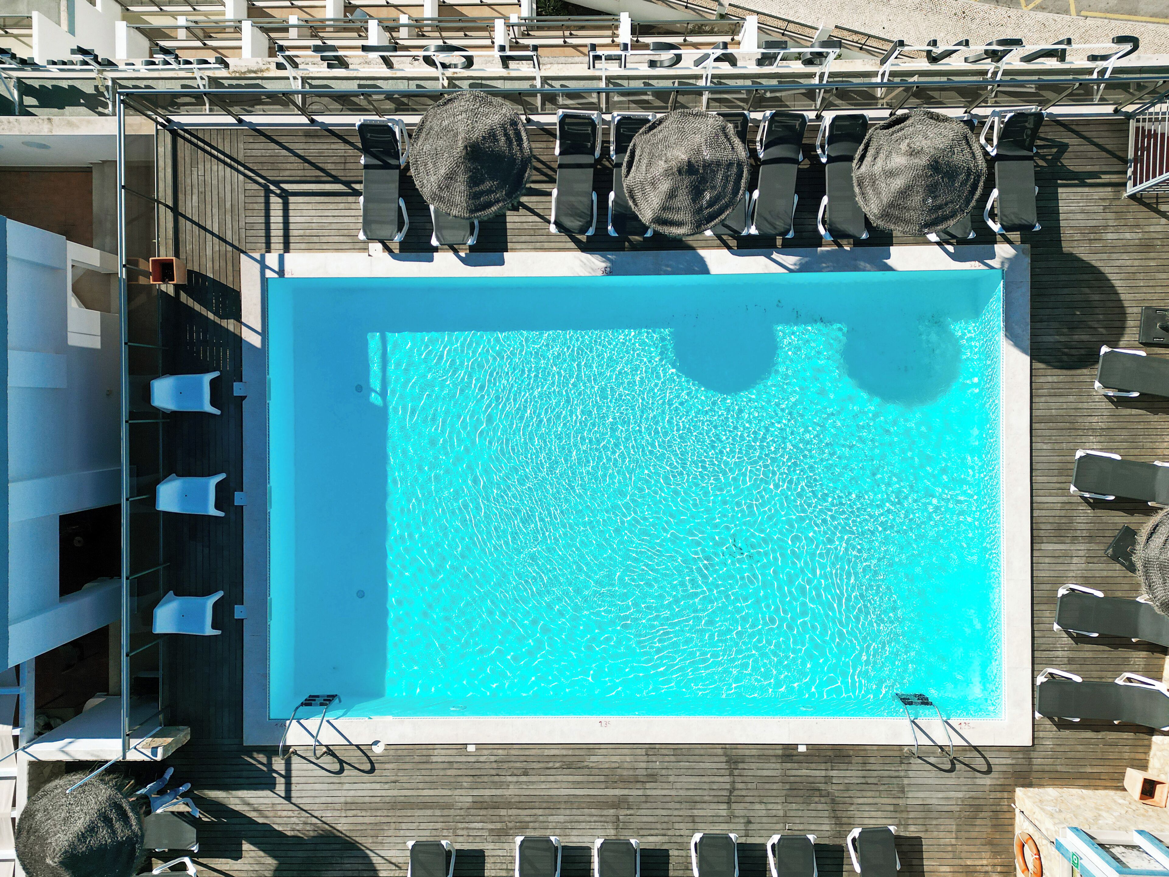 A large, clear blue pool surrounded by lounge chairs and umbrellas on a wooden deck.