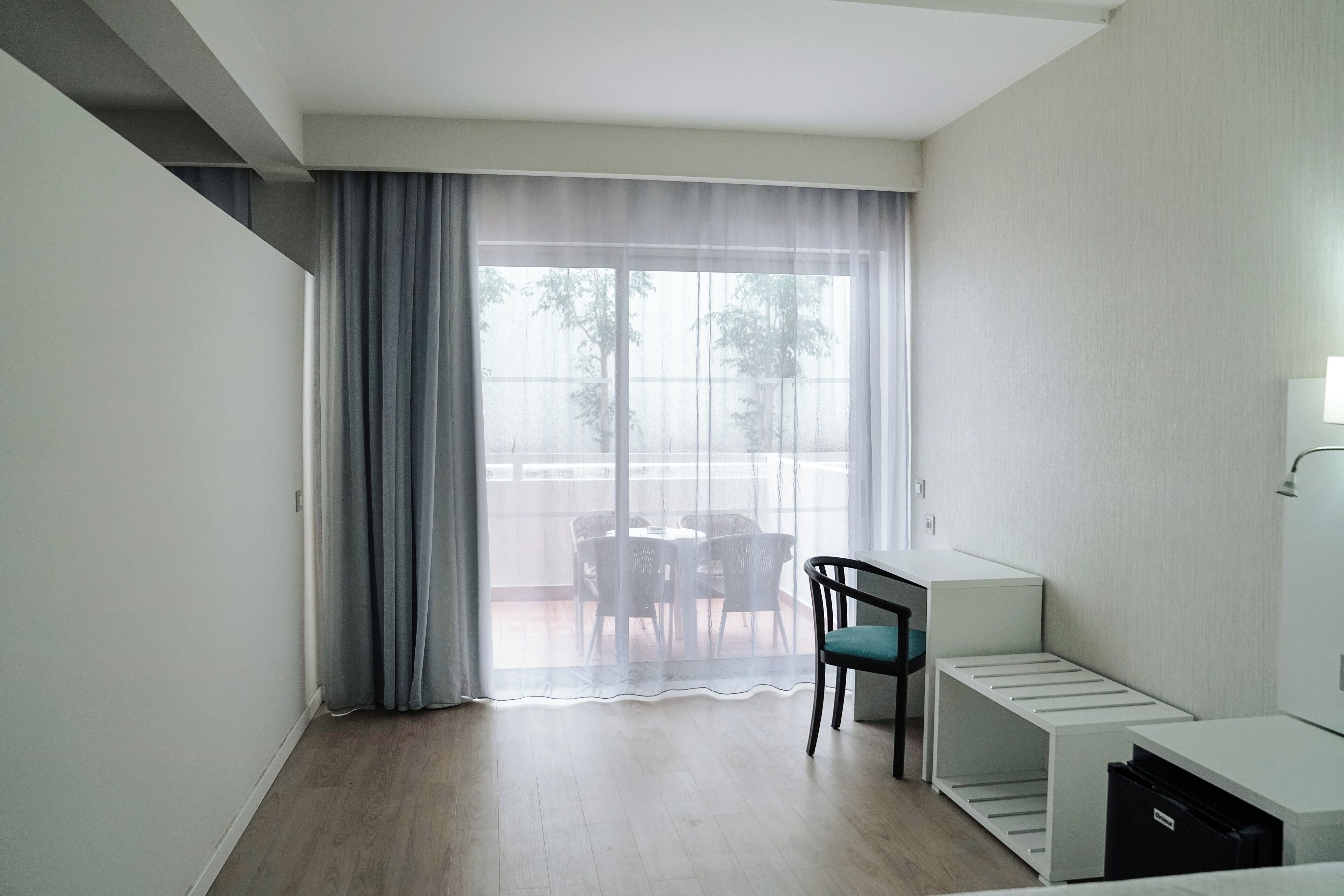 A modern room with a large sliding glass door leading to an outdoor area with a table and chairs.