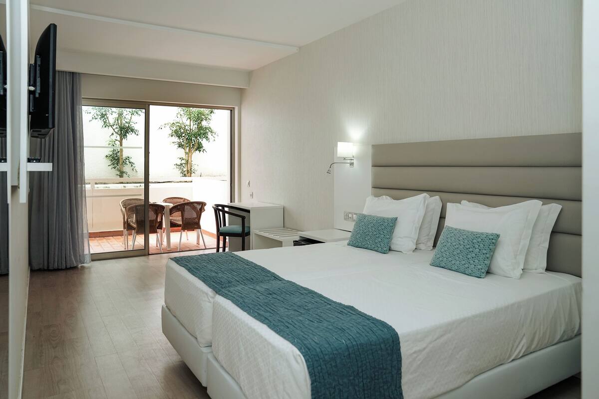 A hotel room with a large bed, a desk, a chair, and a TV.