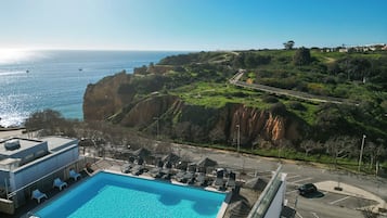 Relax by the infinity pool overlooking the ocean, with a scenic pathway leading to a bridge connecting the property to the mainland.