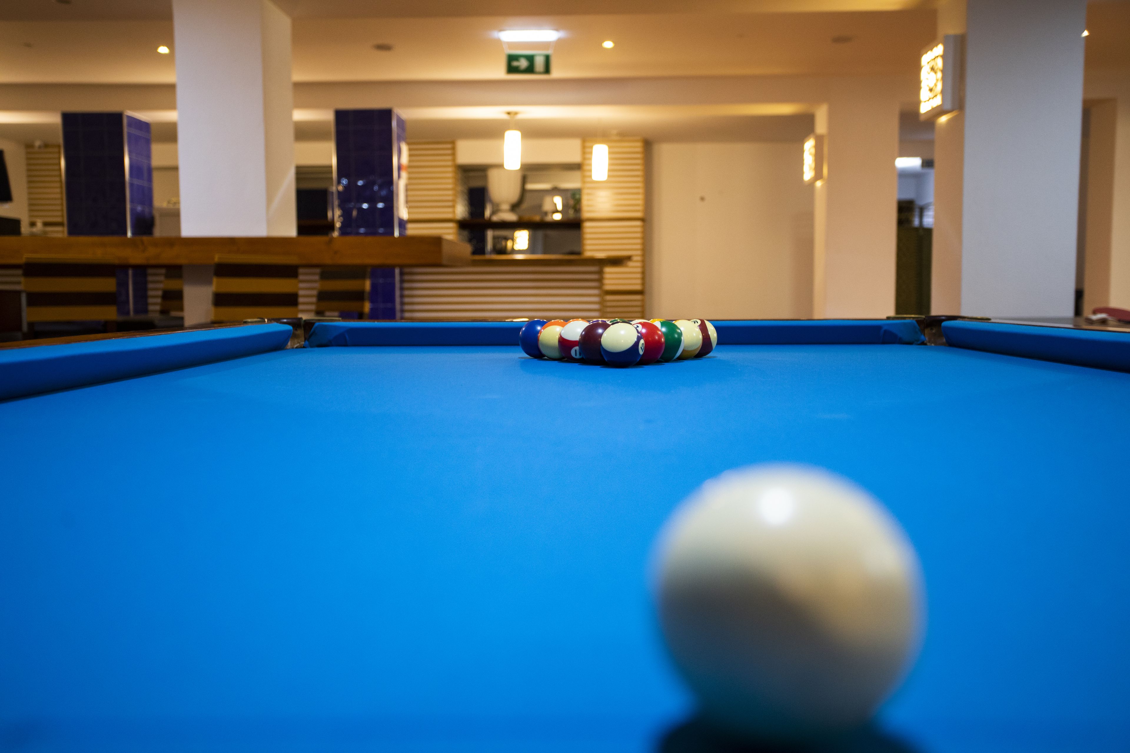 A pool table with a striped cushion and a set of billiard balls.