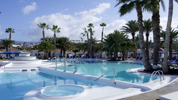 A pool area with lounge chairs and palm trees. - eó Suite Hotel Jardin Dorado (San Bartolomé de Tirajana)