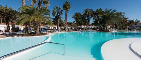 A large swimming pool surrounded by palm trees and lounge chairs.