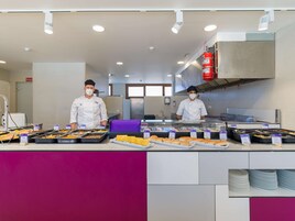 Disposição de buffet com várias bandejas de comida e um extintor fixado na parede.