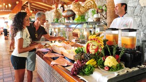 Un bufé con una variedad de frutas, verduras y un chef sirviendo comida.