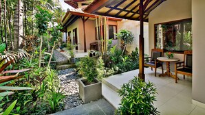 A tropical garden with a covered seating area and a small water feature. - Taman Harum Cottages (Mas)