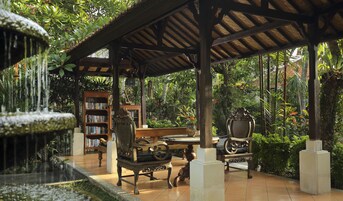 Un espacio al aire libre techado con una fuente, estanterías y asientos.