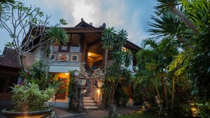 A traditional building with a staircase leading to a covered entrance, surrounded by lush tropical vegetation. - Taman Harum Cottages (Mas)