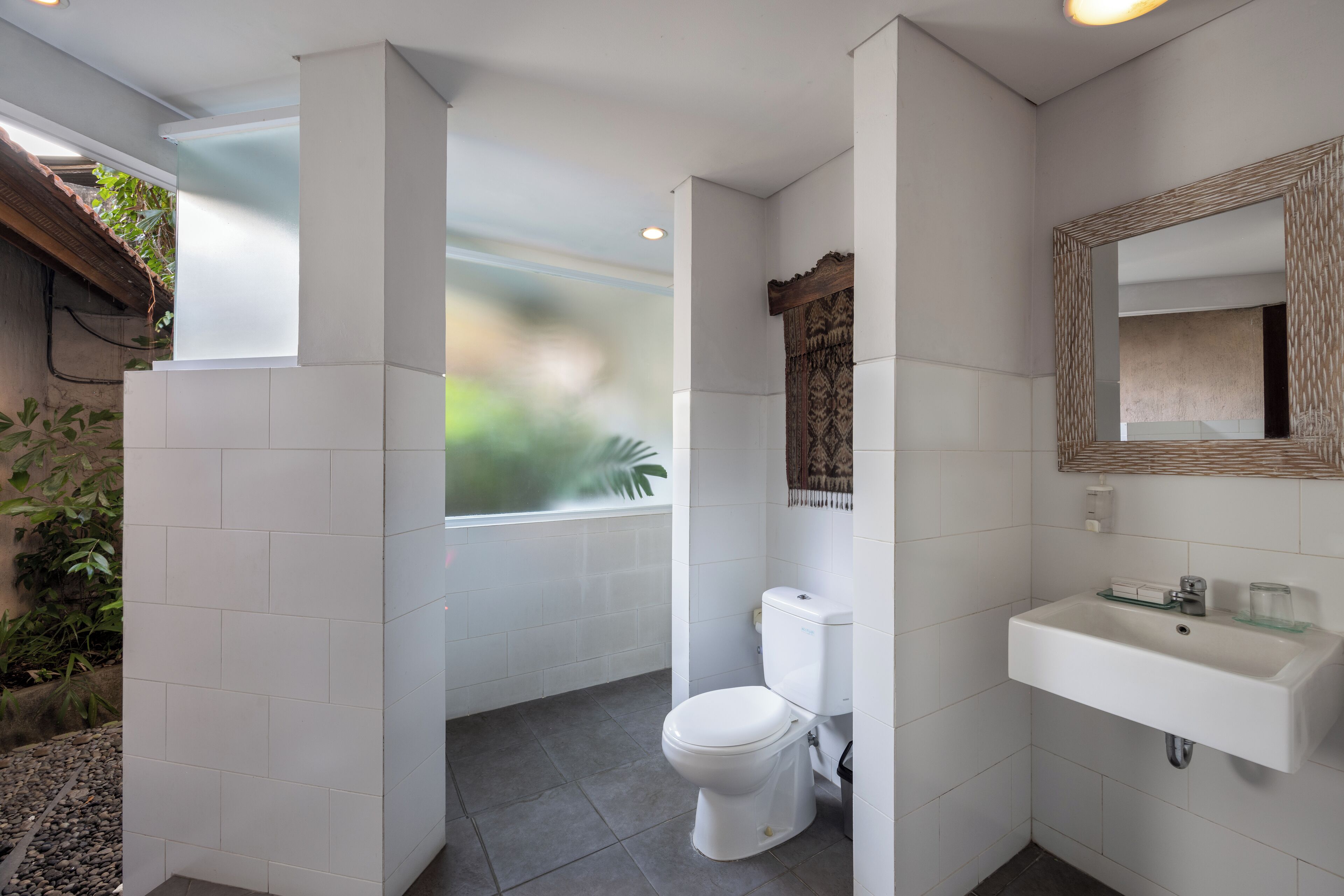 A modern bathroom with a toilet, sink, and a large mirror.