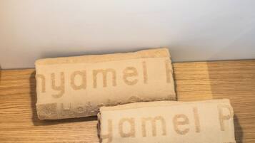 Two towels with embroidered text on a wooden surface, a light switch, and a wall in the background.